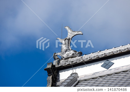 Traditional shachi (mythical fish-like creatures) decorations are placed on top of the white walls and tiled roof. Traditional shachi (mythical fish-like creatures) decorations are placed on top of the white walls and tiled roof. 141870486