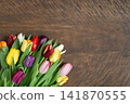 A beautiful bouquet of tulips on dark brown wooden background with copy space. Beautiful colorful spring flowers. View from above. 141870555