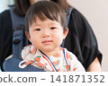 一名身穿西瓜圖案甚平的日本男嬰被放在嬰兒背帶裡參加節慶活動。 一名身穿西瓜圖案甚平的日本男嬰被放在嬰兒背帶裡參加節慶活動。 141871352