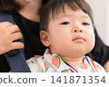 一名身穿西瓜圖案甚平的日本男嬰被放在嬰兒背帶裡參加節慶活動。 一名身穿西瓜圖案甚平的日本男嬰被放在嬰兒背帶裡參加節慶活動。 141871354