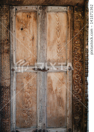 Rustic carved wooden door with traditional decorative details and aged texture Rustic carved wooden door with traditional decorative details and aged texture 141871362
