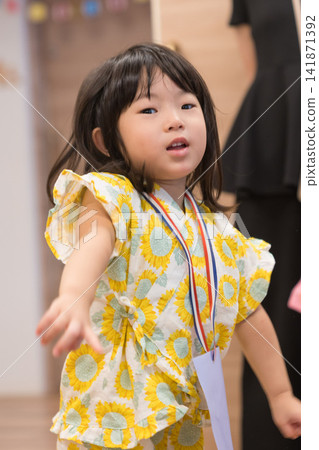 身穿向日葵圖案甚平（日本傳統夏季服裝）的日本女孩正在參加夏季祭典活動。 141871392