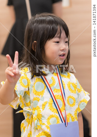 身穿向日葵圖案甚平（日本傳統夏季服裝）的日本女孩正在參加夏季祭典活動。 141871394