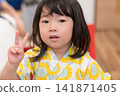 身穿向日葵圖案甚平(日本傳統夏季服裝)的日本女孩正在參加夏季祭典活動。 身穿向日葵圖案甚平(日本傳統夏季服裝)的日本女孩正在參加夏季祭典活動。 141871405