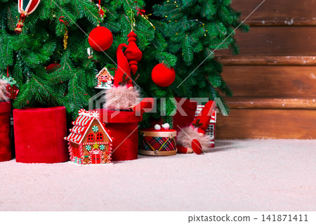 Cozy Christmas tree with festive decorations and gifts in a warm room Cozy Christmas tree with festive decorations and gifts in a warm room 141871411
