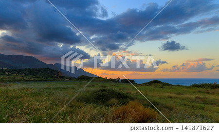 Scenic coastal valley with rolling hills and dramatic sunset clouds over the sea Scenic coastal valley with rolling hills and dramatic sunset clouds over the sea 141871627