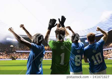 Soccer players facing stadium stands from behind and waving to fans, raised arms to greet supporters before football match. Teammates in blue and green jersey, goalkeeper captain. 141871827