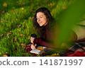 Person writes notes lying on the lawn in the autumn park. Solitude with yourself 141871997