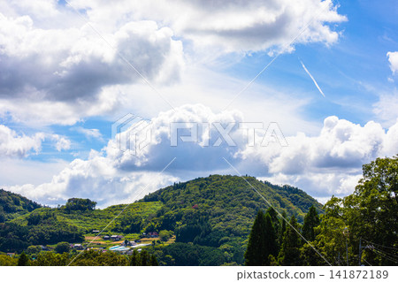 A blue sky filled with contrails and rising summer clouds. A blue sky filled with contrails and rising summer clouds. 141872189