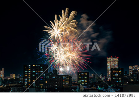 The Okazaki Fireworks Festival blooming in the night sky, with an aerial view of towering apartment buildings. The Okazaki Fireworks Festival blooming in the night sky, with an aerial view of towering apartment buildings. 141872995