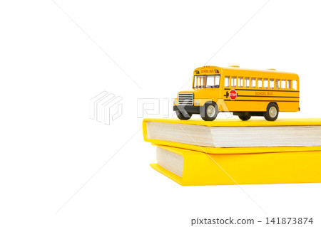 A school bus sits on top of two stacked books, isolated on white, PNG A school bus sits on top of two stacked books, isolated on white, PNG 141873874