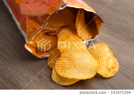 Potato chips, delicious BBQ seasoning spicy for crips, thin slice deep fried snack fast food in open bag. Potato chips, delicious BBQ seasoning spicy for crips, thin slice deep fried snack fast food in open bag. 141875294