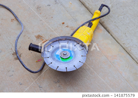 Power saw tool lies on cement slab at construction site, wear after work is done. 141875579