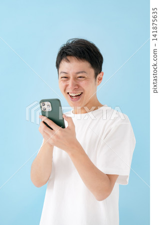 A man looking at a smartphone with a smile A man looking at a smartphone with a smile 141875635