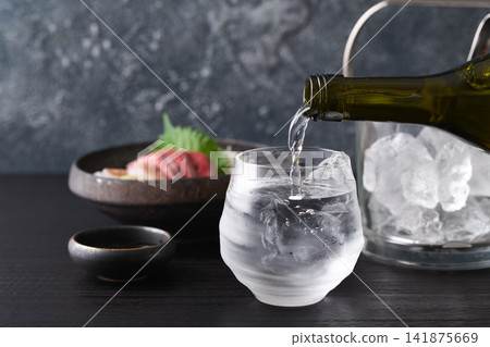 將燒酒倒入玻璃杯中。 將燒酒倒入玻璃杯中。 141875669