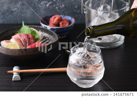 將燒酒倒入玻璃杯中。 將燒酒倒入玻璃杯中。 141875671