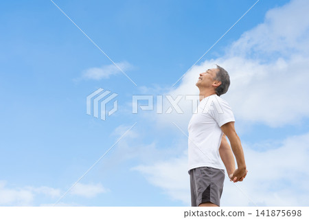 A man stretching under a blue sky A man stretching under a blue sky 141875698