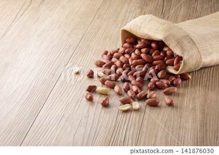 Peanuts with their skins on overflowing from a burlap sack Peanuts with their skins on overflowing from a burlap sack 141876030