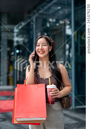 Asian Woman Talking on Smartphone while Shopping Outdoors Asian Woman Talking on Smartphone while Shopping Outdoors 141876230