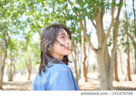 一位日本女子在公園裡轉身微笑。 一位日本女子在公園裡轉身微笑。 141876788