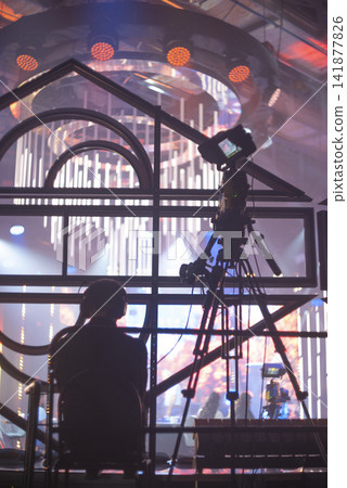 Backstage view of cameraman filming live event on stage under stadium lights with copy space Backstage view of cameraman filming live event on stage under stadium lights with copy space 141877826