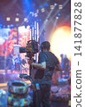 Steadicam operator filming live performance on stage with camera stabilizer and copy space 141877828