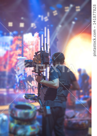 Steadicam operator filming live performance on stage with camera stabilizer and copy space 141877828