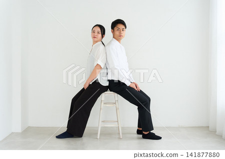 Young men and women lined up in front of a white wall. Young men and women lined up in front of a white wall. 141877880