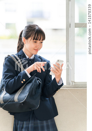 Smiling middle school and high school girls using smartphones in the school hallway (crime prevention, safety, security) 141878339
