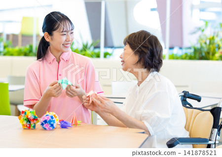 照顧畫面：一位老婦人在照顧者的陪伴下摺紙。攝影協助：東京電子電波學園大學 141878521