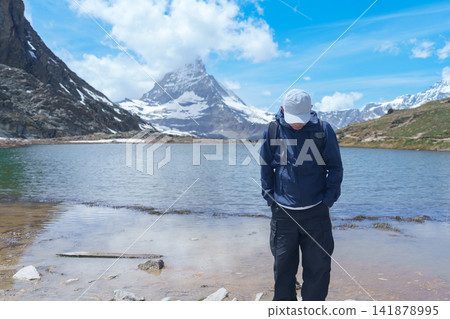 man Tourist Exploring Zermatt, Switzerland. happy hiker sightseeing iconic Matterhorn Swiss Alps at Riffelsee Lake, Famous European Landmark, Hiking Attraction and Travel Destination in Europe man Tourist Exploring Zermatt, Switzerland. happy hiker sightseeing iconic Matterhorn Swiss Alps at Riffelsee Lake, Famous European Landmark, Hiking Attraction and Travel Destination in Europe 141878995