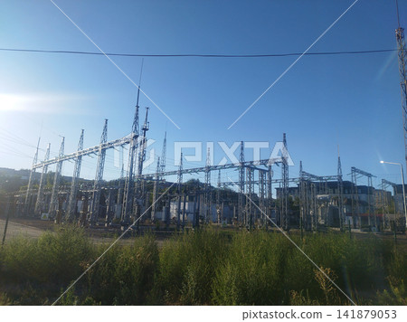 A complex urban electrical substation view with steel lattice structures, transformers, and intricate overhead lines. A complex urban electrical substation view with steel lattice structures, transformers, and intricate overhead lines. 141879053