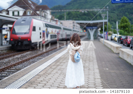 Woman Tourist Explore Interlaken West Railway Station, Switzerland in Summer. Traveler Watch a Swiss Train with Mountain and Town, Famous European Tourist Attraction and Europe Travel Destination Woman Tourist Explore Interlaken West Railway Station, Switzerland in Summer. Traveler Watch a Swiss Train with Mountain and Town, Famous European Tourist Attraction and Europe Travel Destination 141879110