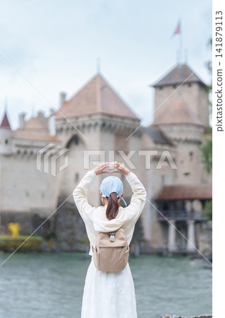 Woman Tourist Explore Chateau de Chillon, Montreux, Switzerland in Summer. Traveler Making Heart Shape at Castle on Lake Geneva, Famous European Tourist Attraction and Europe Travel Destination Woman Tourist Explore Chateau de Chillon, Montreux, Switzerland in Summer. Traveler Making Heart Shape at Castle on Lake Geneva, Famous European Tourist Attraction and Europe Travel Destination 141879113