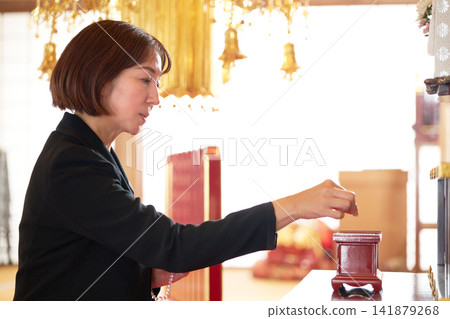 A woman in mourning clothes offering incense. A woman in mourning clothes offering incense. 141879268