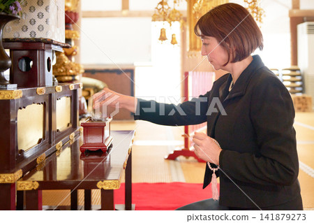 A woman in mourning clothes offering incense. A woman in mourning clothes offering incense. 141879273