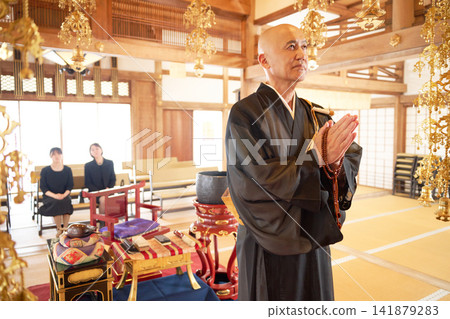 A monk offering prayers, watched by the mourners. A monk offering prayers, watched by the mourners. 141879283