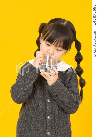Asian little girl holds a glass of water, promoting hydration, healthy drinking habit, child lifestyle concept Asian little girl holds a glass of water, promoting hydration, healthy drinking habit, child lifestyle concept 141879666