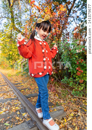 Asian girl walking on railway track in autumn park, calm and playful emotion, childhood exploration and balance concept Asian girl walking on railway track in autumn park, calm and playful emotion, childhood exploration and balance concept 141879677