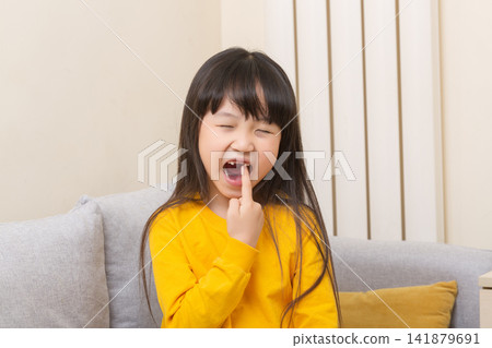 Asian girl pointing to open mouth with tooth pain, child showing dental problem at home, healthcare concept Asian girl pointing to open mouth with tooth pain, child showing dental problem at home, healthcare concept 141879691