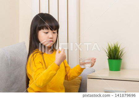 Asian girl taking medicine with water sick child healthcare treatment concept 141879696