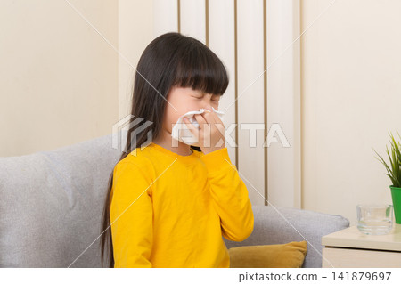 Asian girl blowing nose with tissue sick child flu cold healthcare concept Asian girl blowing nose with tissue sick child flu cold healthcare concept 141879697