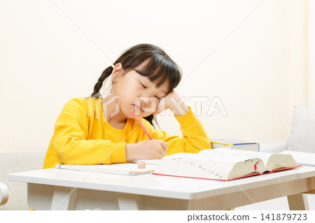Tired Asian Girl Doing Homework at Desk, Focused Study and Learning Concept Tired Asian Girl Doing Homework at Desk, Focused Study and Learning Concept 141879723