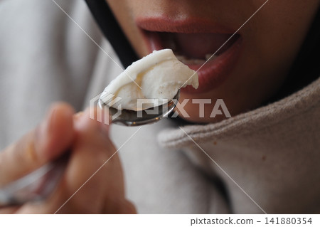 Person eats dessert with a spoon in a cafe 141880354