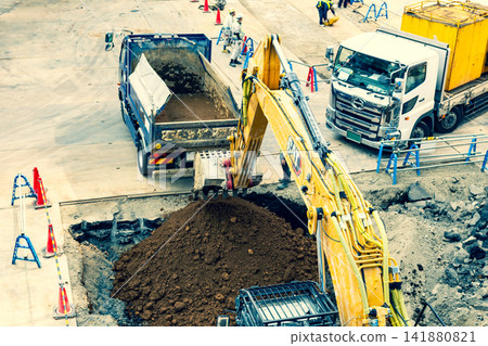 Vehicles working at a construction site: excavators and dump trucks; warm and cool colors emphasized. Vehicles working at a construction site: excavators and dump trucks; warm and cool colors emphasized. 141880821