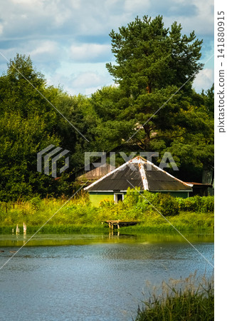 Authentic Russian province landscape with a traditional village house by a lake. 141880915