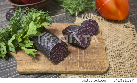 Traditional smoked sausage with fresh dill and tomatoes on a rustic wooden table. 141881187