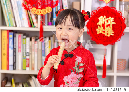 Smiling Asian Child Holding Traditional Rice Crust Snacks for Spring Festival,The text on the pendant hanging at the back reads: "Happy New Year." Smiling Asian Child Holding Traditional Rice Crust Snacks for Spring Festival,The text on the pendant hanging at the back reads: "Happy New Year." 141881249