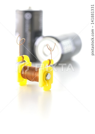 A coil and a dry cell battery are photographed against a white background. A coil and a dry cell battery are photographed against a white background. 141881331