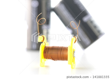 A coil and a dry cell battery are photographed against a white background. A coil and a dry cell battery are photographed against a white background. 141881335